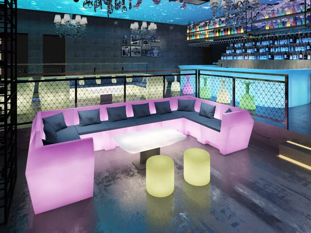 Sofás y mesas LED luminosas en discoteca con ambiente moderno